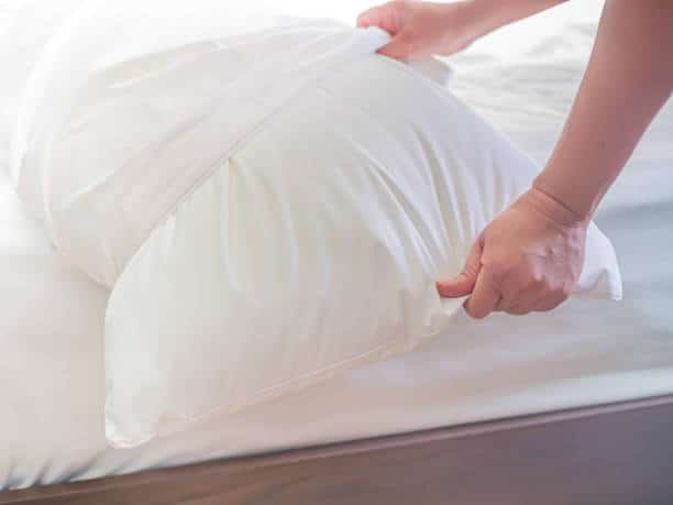 A picture of a man changing a pillow case