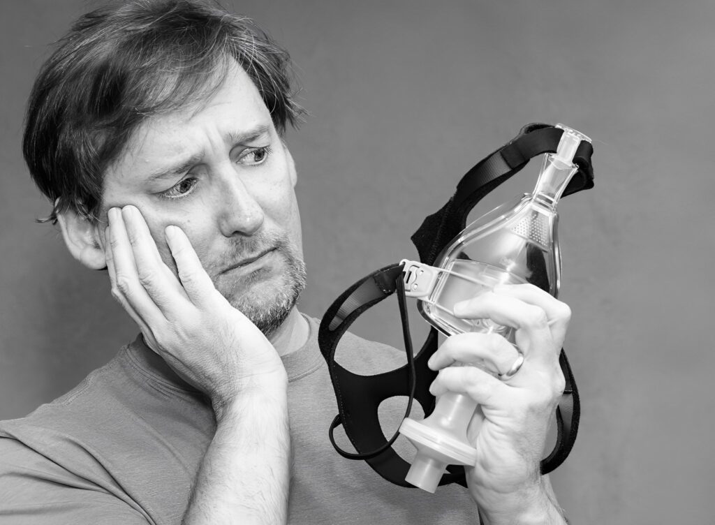 A picture of a man looking at his CPAP mask.