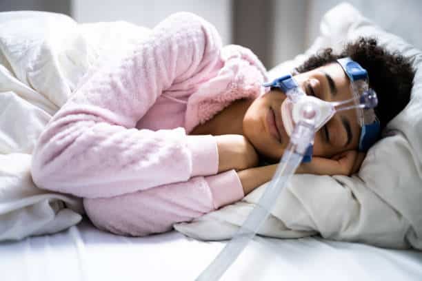 A picture of a woman sleeping using her CPAP machine.