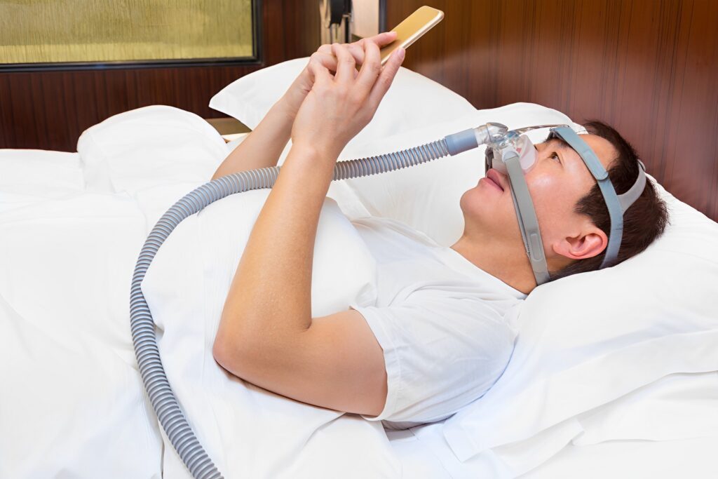 A picture of a man using CPAP machine and nasal mask