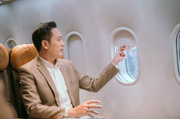 A businessman looks at the window on a plane while traveling abroad.