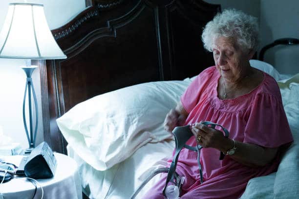 A picture of a senior woman holding a CPAP Mask